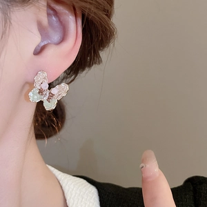 Detail view of sweet butterfly stud earring with pink and green crystal stones on ear