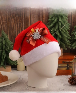 Detail of red plush Christmas hat featuring a brown Merry Christmas ribbon and silver snowflake