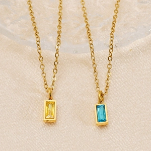 Detail of emerald cut rectangle birthstone pendants on a gold O-chain necklace