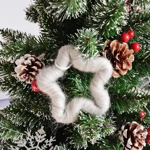 Detail of grey fuzzy star ornament with wool texture hanging on a lush Christmas tree branch