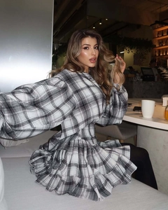 Detailed view of black and white plaid dress featuring tiered ruffle hem and long sleeves