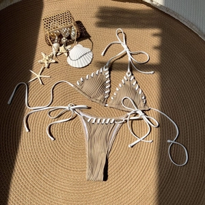 Detail view of khaki textured two-piece bikini with white lacing and ribbed fabric texture