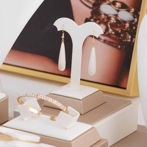Elegante espositore per gioielli con orecchini bianchi a goccia e bracciale in oro e diamanti