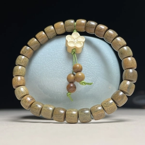 Nahaufnahme von grünen Sandelholzperlen mit Pflaumenblüten-Anhänger auf Porzellan