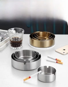Stack of gold and silver stainless steel ashtrays with brushed finish and three cigarette slots