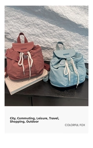 Detail of mini nylon bucket backpacks in red and blue with thick white drawstring cords