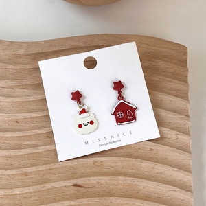 Detail of Christmas earrings featuring a white bear and red cabin on a white card