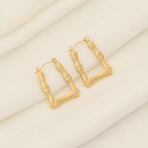 Elegante goldene geometrische Ohrringe im Bambus-Stil auf weißer Seide