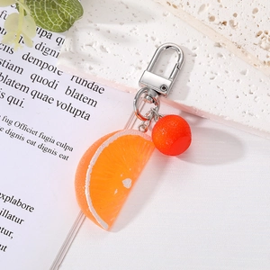 Macro shot of realistic orange slice resin keychain with silver metal clasp on a textured surface