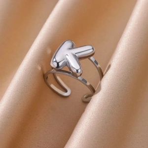 Detailed macro view of a silver balloon-style letter K ring on champagne silk fabric