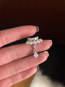 Detail of silver drop earring with white pearls and a sparkling zircon teardrop pendant