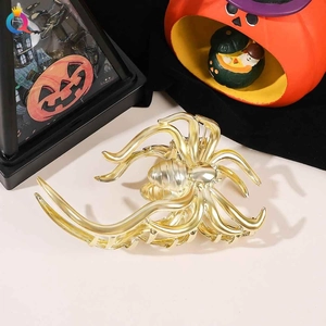Close-up of golden metal spider hair claw clip with festive Halloween pumpkin decorations