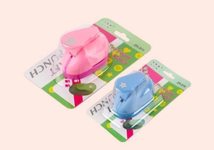 Detail view of pink heart and blue star paper punches in retail blister packaging