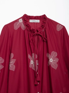 Detail of raspberry embroidered shirt showing ruffled collar with tie and brand size label