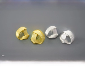 Detail of geometric triangle stud earrings in gold and silver with a brushed metal finish