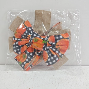 Close-up of Thanksgiving bow with black and white plaid pumpkin patterns and burlap layers