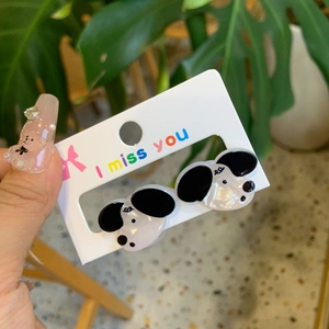 Macro shot of cute cartoon dog acrylic stud earrings on a white branded display card