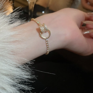 Gros plan d'un bracelet doré orné de zircons porté au poignet avec manche en fourrure