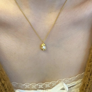 Close-up of golden bean pearl necklace on model with elegant French style vibes