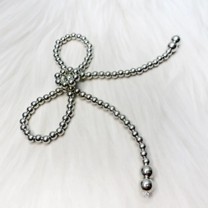 Detailed view of silver beaded bow accessory on white faux fur background
