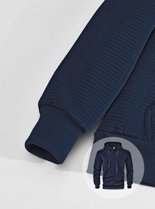 Gros plan détaillé sur la texture à chevrons bleu marine et les poignets du sweat à capuche