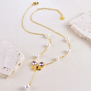 Collier doré élégant orné de perles blanches et d'un pendentif papillon en cristal violet