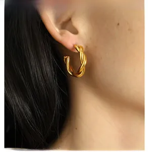 Detailed view of gold twisted C-shape hoop earrings featuring a braided spiral design