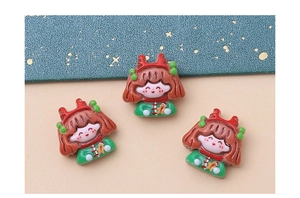 Close-up of three cute Christmas resin charms featuring little girls with green antlers