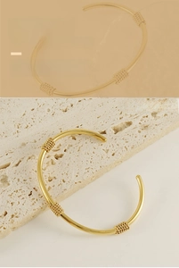 Detail of 18K gold plated stainless steel open bangle with triple twisted rope accents