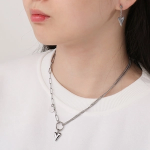Detail of silver heart pendant necklace and matching earrings set on model