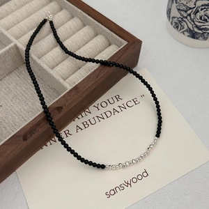 Minimalist black onyx and silver beaded necklace displayed on a wooden jewelry box