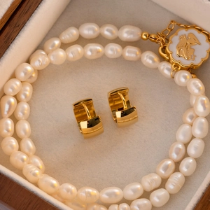 Detail showing polished 18K gold earrings and double-layer pearl necklace on velvet liner