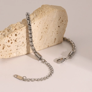 Detailed view of silver woven chain bracelet with lobster clasp on natural stone texture