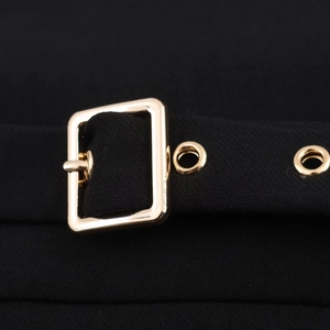 Détail d'une ceinture en tissu noir avec boucle dorée polie et œillets métalliques