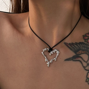 Macro shot of a silver lava-style heart pendant necklace with irregular texture on black cord