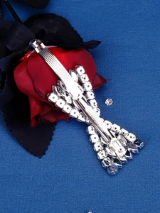 Detail of silver bow hair clip with crystal tassels resting on a decorative fabric flower