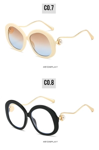 Detail of retro round pearl sunglasses in cream and black with gold metal arms