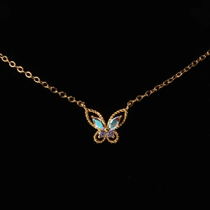 Macro shot of gold butterfly pendant with iridescent blue and purple gemstones