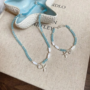Ensemble collier et bracelet en perles bleues avec pendentifs étoile de mer sur plat