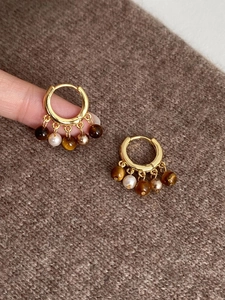 Détail de créoles plaquées or 18 carats avec breloques en œil de tigre et perles