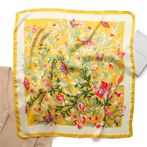 Gedetailleerde close-up van een zijden sjaal met bloemen- en vlinderprint en satijnglans