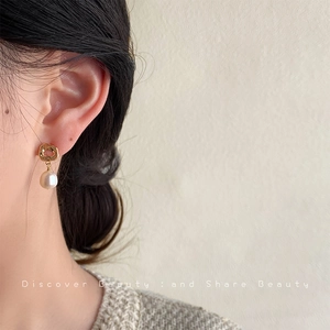 Baroque natural pearl earrings with gold hammered metal pieces on female model