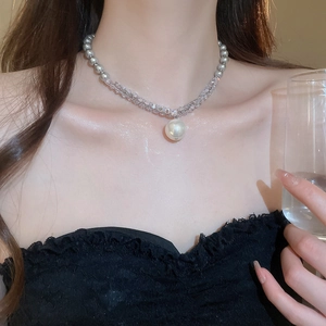 Detail of grey beaded necklace with crystal accents and large pearl pendant on neck