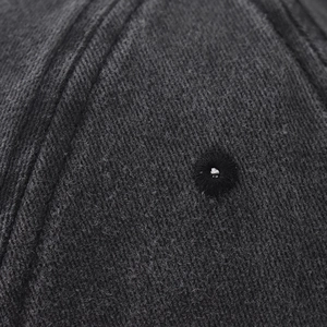 Détail de l'œillet brodé et texture vintage délavée sur la casquette en sergé épais