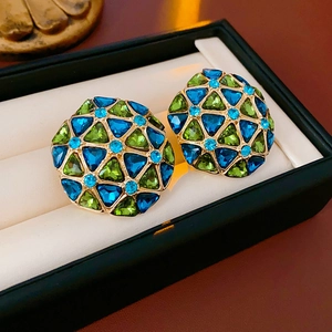 Macro detail of vintage geometric earrings with blue and green crystals in golden metal