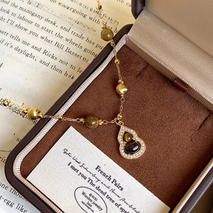 18K gold plated tiger eye wulu necklace with crystal pavé on a vintage jewelry box