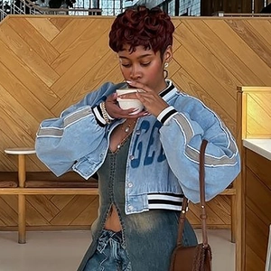 Detailed view of a cropped denim jacket with grey sleeve stripes and rib-knit cuffs