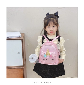 Close-up of a pink unicorn backpack with sparkling stars on a little girl model