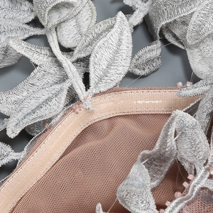 Macro detail of silver floral embroidery on nude mesh fabric of an evening gown