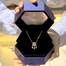 Close-up of rose gold dreamcatcher necklace with feathers in a blue jewelry box